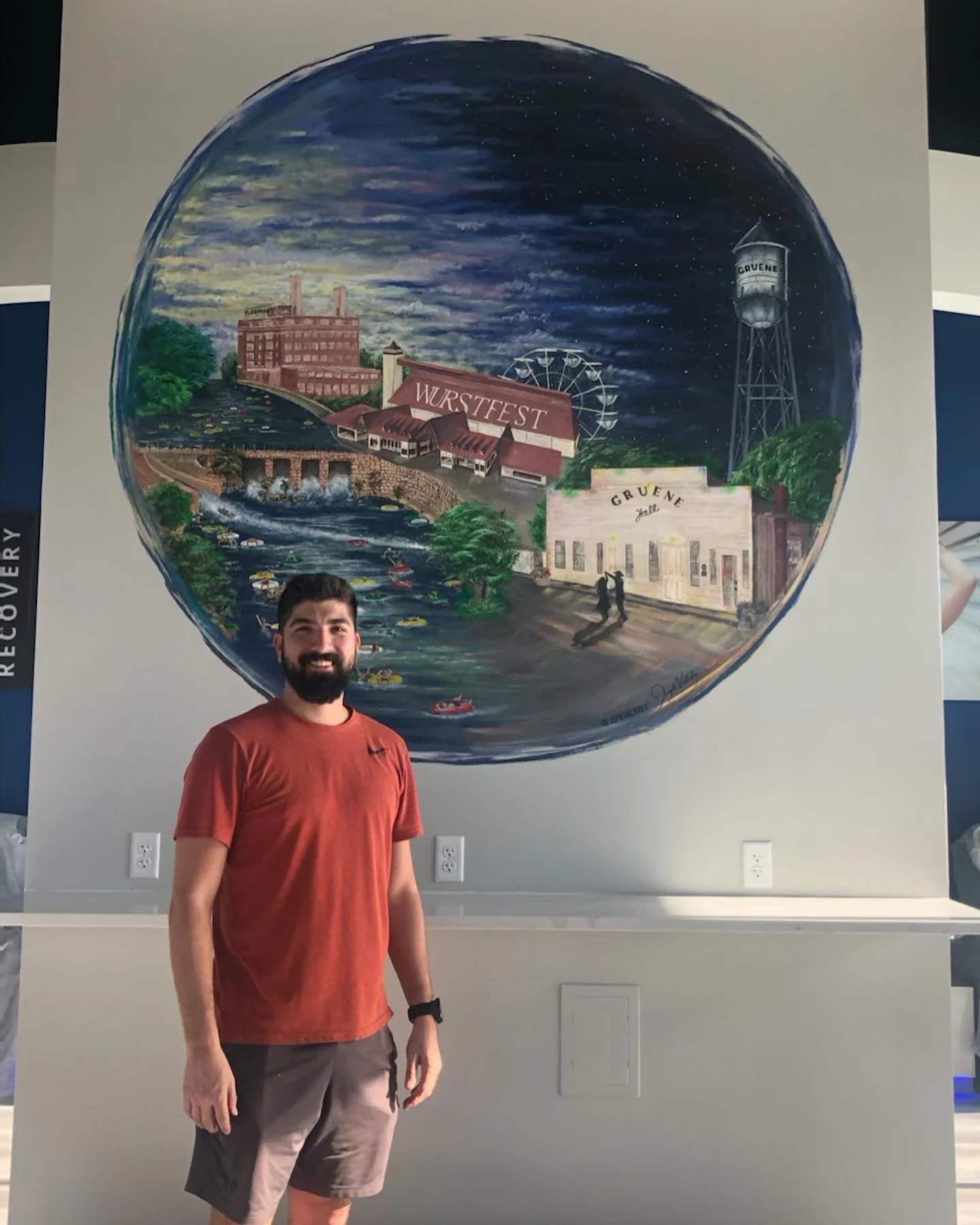 Joseph Valadez standing in front of his completed iCRYO New Braunfels mural